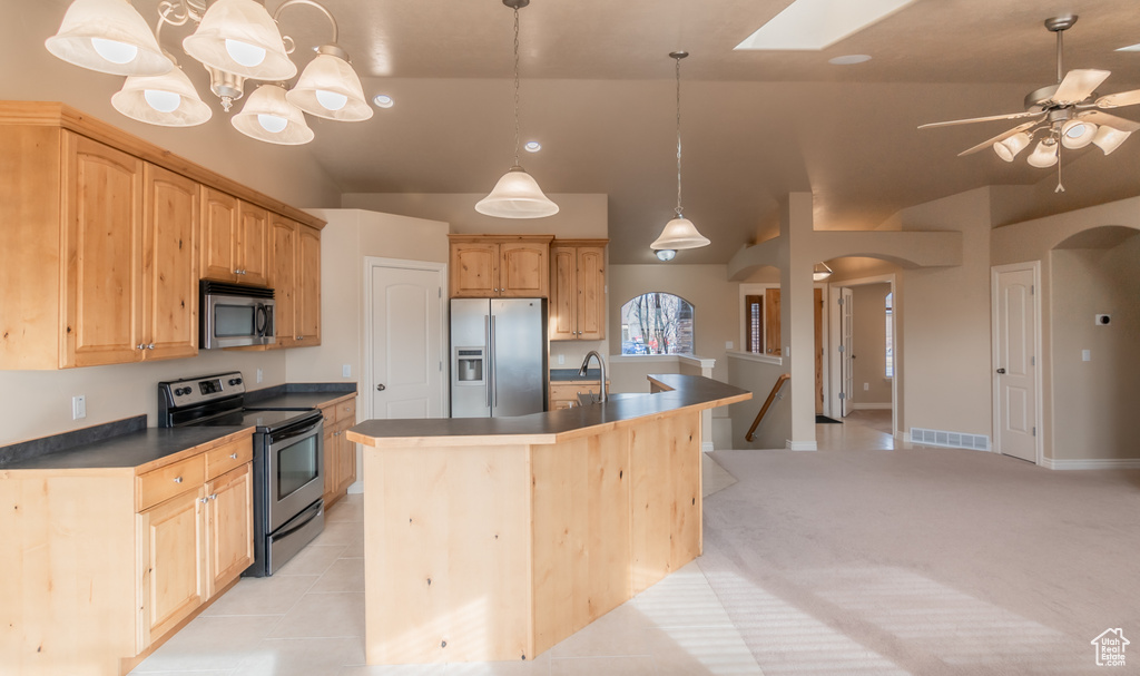 Kitchen featuring dark countertops, arched walkways, an island with sink, visible vents, and appliances with stainless steel finishes