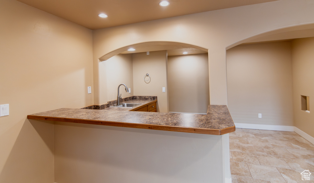 Kitchen with baseboards, recessed lighting, arched walkways, and a sink