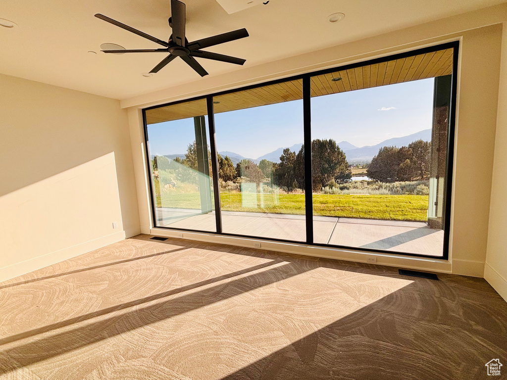 Spare room featuring ceiling fan, a water and mountain view, and carpet