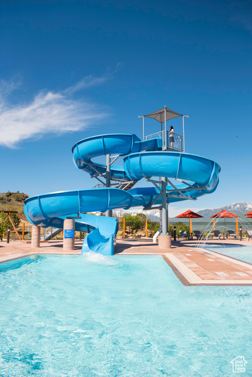 Pool featuring fence, a water slide, and a water play area