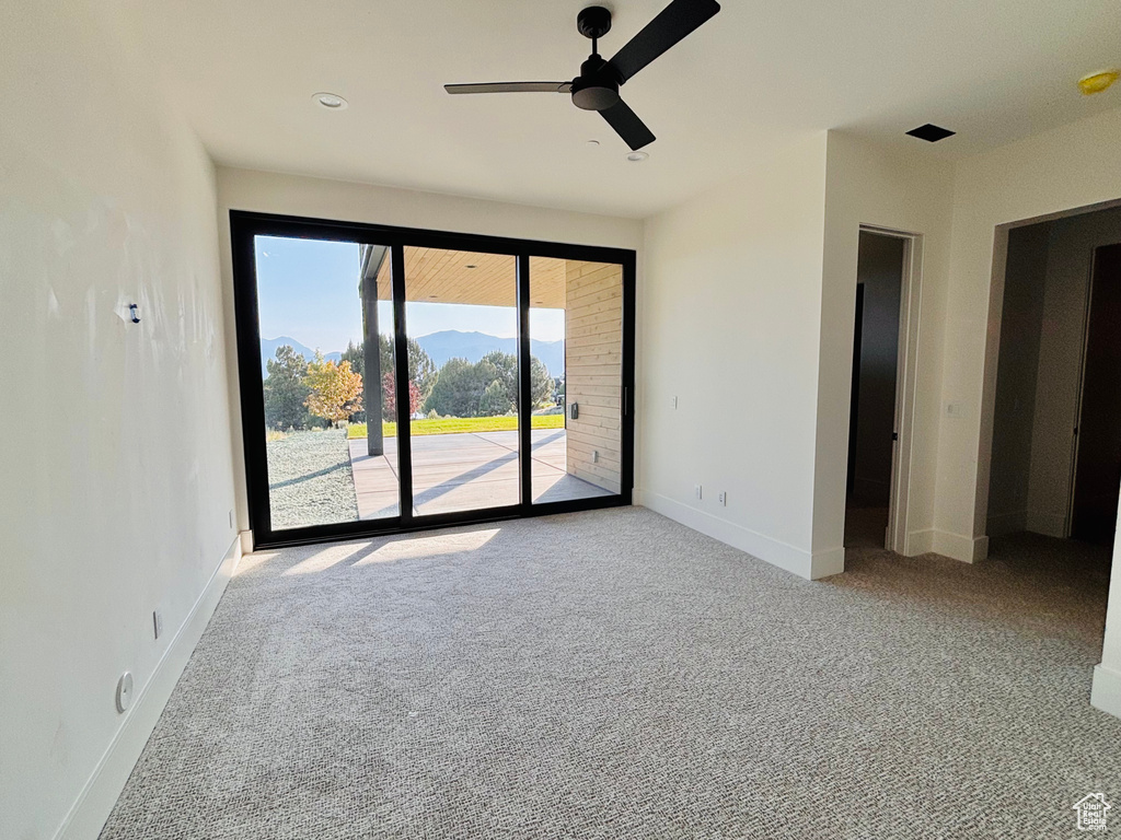 Carpeted empty room featuring ceiling fan and baseboards