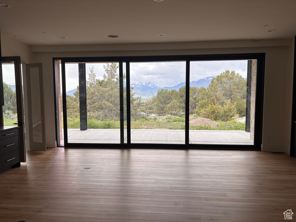 Empty room with wood finished floors, a mountain view, and recessed lighting