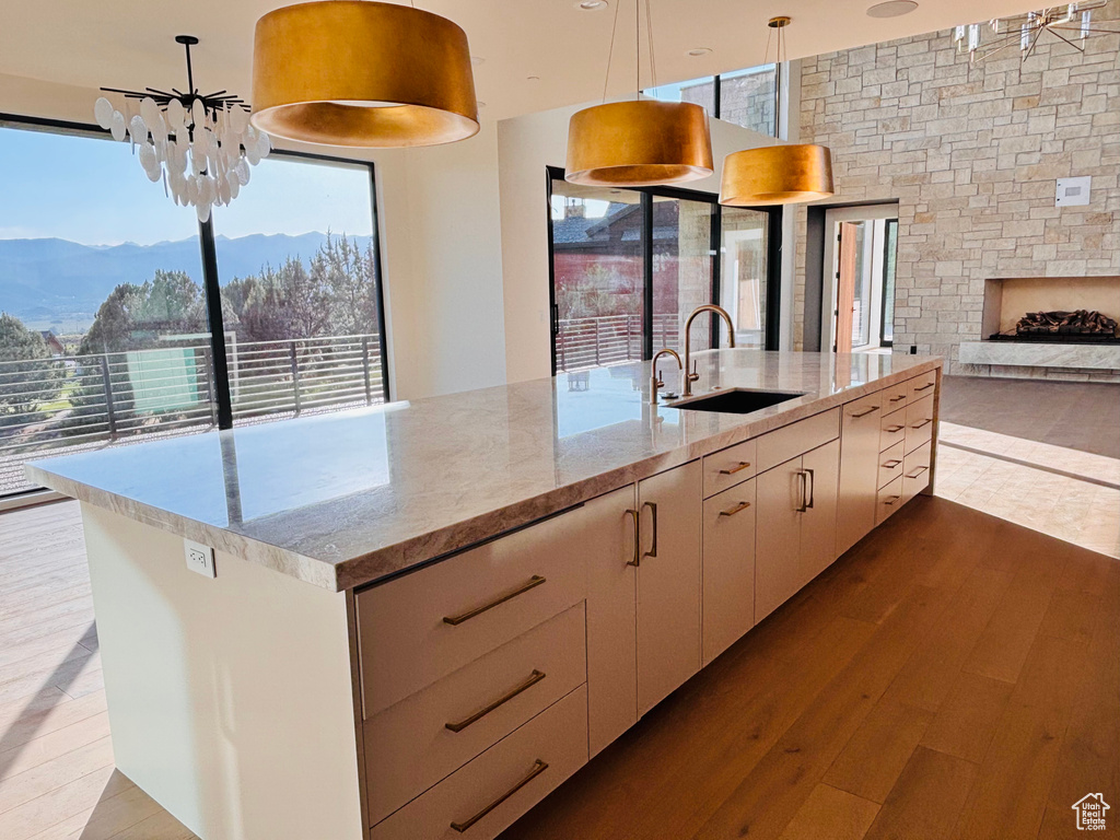 Kitchen featuring a mountain view, wood-type flooring, a fireplace, light stone counters, and open floor plan