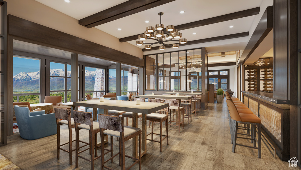 Dining room featuring a notable chandelier, light wood finished floors, a community bar, beamed ceiling, and a mountain view