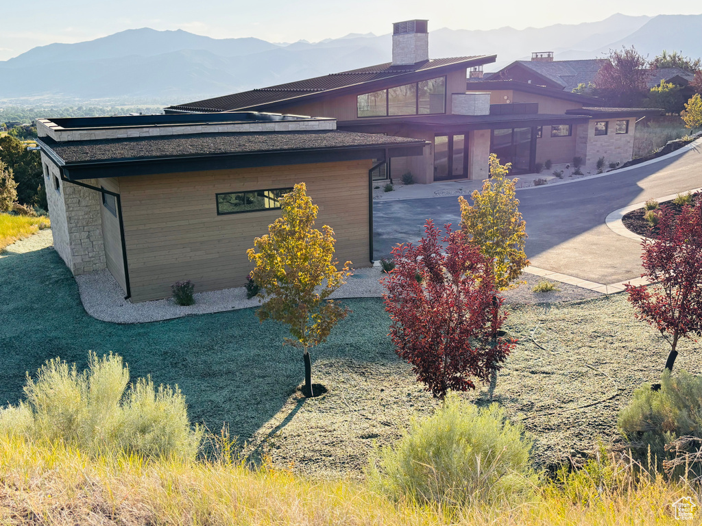 View of side of property with a mountain view, a chimney, and stone siding