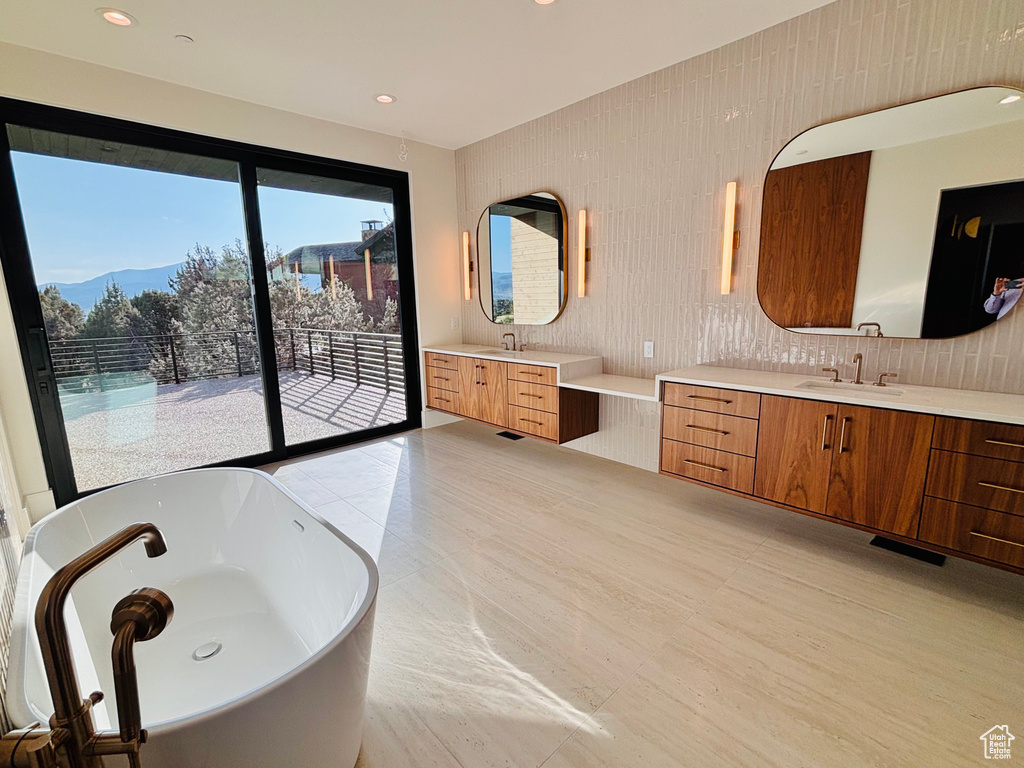 Bathroom with a freestanding tub, two vanities, a mountain view, decorative backsplash, and recessed lighting