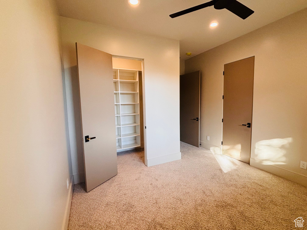 Unfurnished bedroom with a spacious closet, carpet, recessed lighting, and a ceiling fan