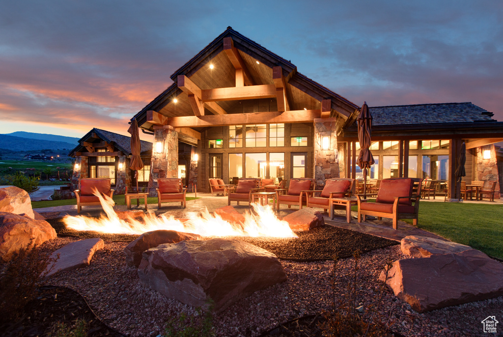Rear view of property featuring an outdoor living space with a fire pit, a patio area, and stone siding