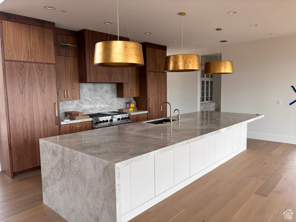 Kitchen featuring a sink, modern cabinets, stove, and light wood-style floors