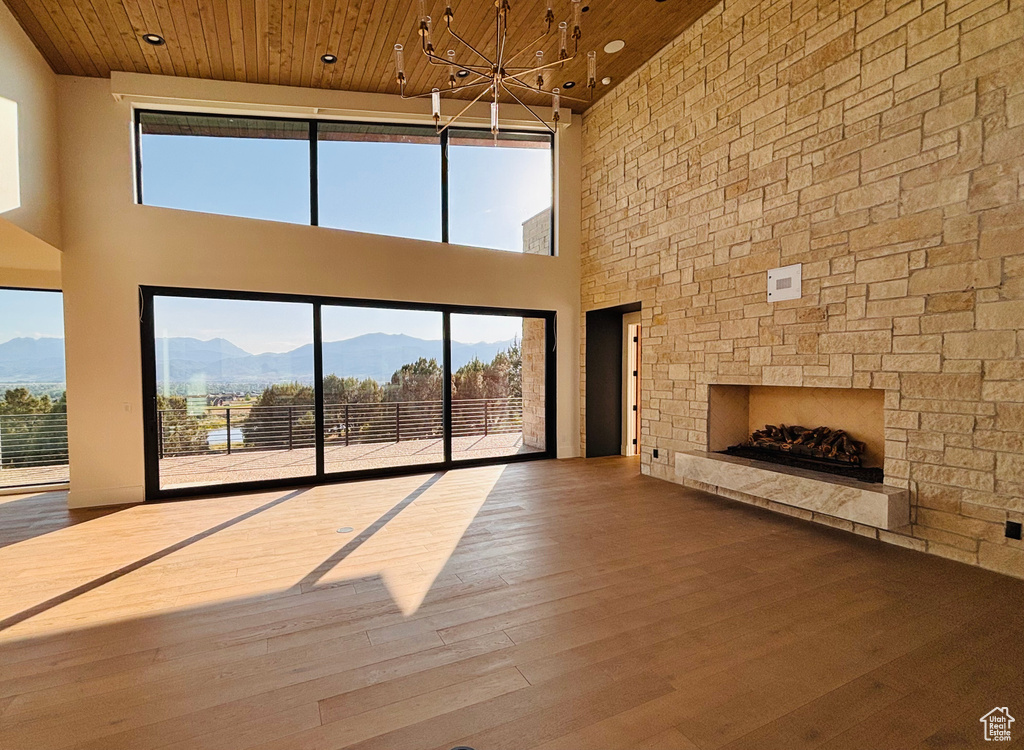 Unfurnished living room with a towering ceiling, a mountain view, a chandelier, wood ceiling, and wood finished floors