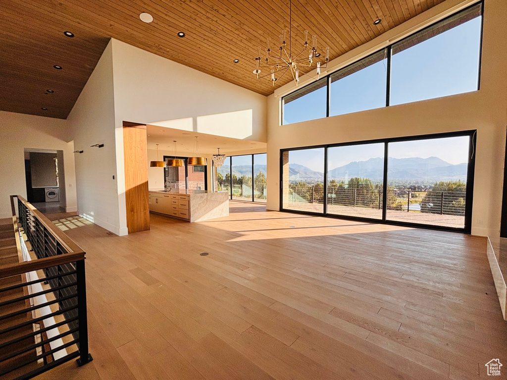 Unfurnished living room with high vaulted ceiling, a chandelier, a mountain view, wooden ceiling, and hardwood / wood-style floors