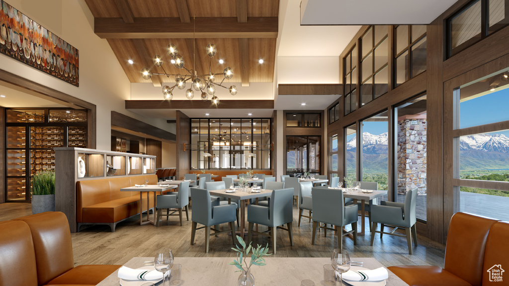 Dining space with a towering ceiling, beam ceiling, wood finished floors, a mountain view, and an inviting chandelier