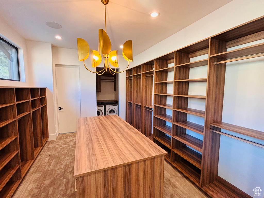 Spacious closet with washing machine and clothes dryer, a chandelier, and light wood-type flooring