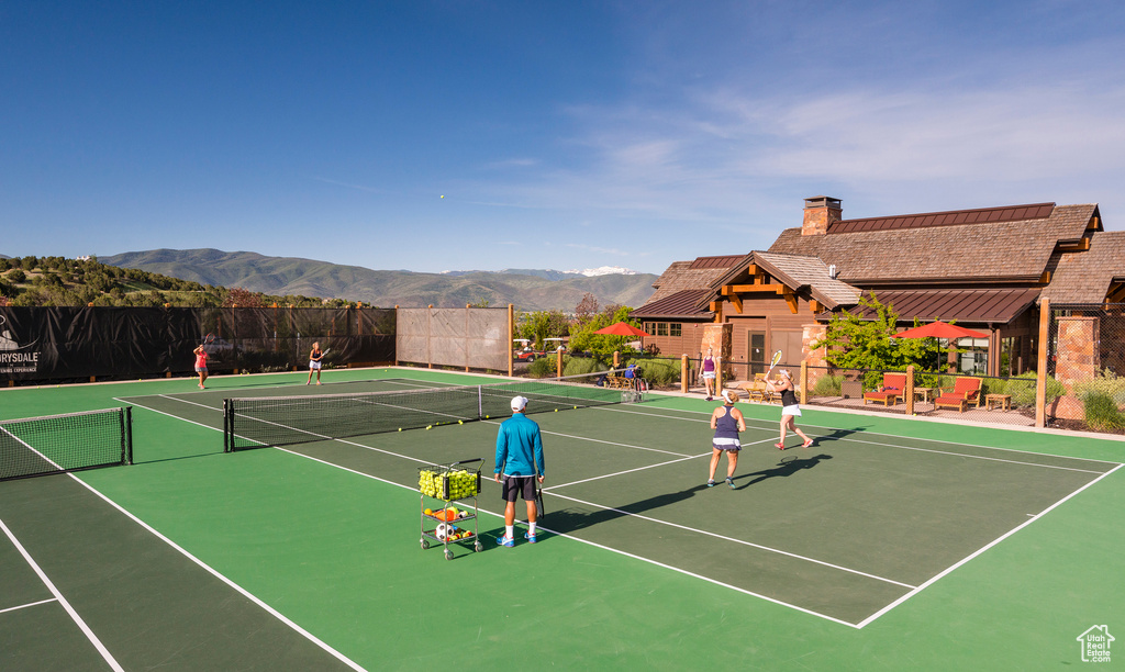 View of tennis court featuring community basketball court, fence, and a mountain view