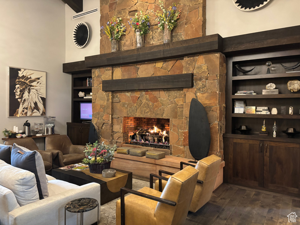 Living area featuring a towering ceiling, dark wood finished floors, built in features, and a fireplace