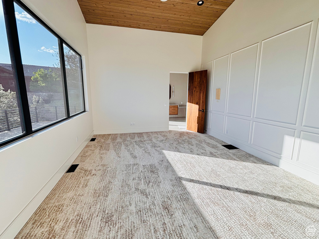 Unfurnished bedroom with wood ceiling, carpet floors, and high vaulted ceiling