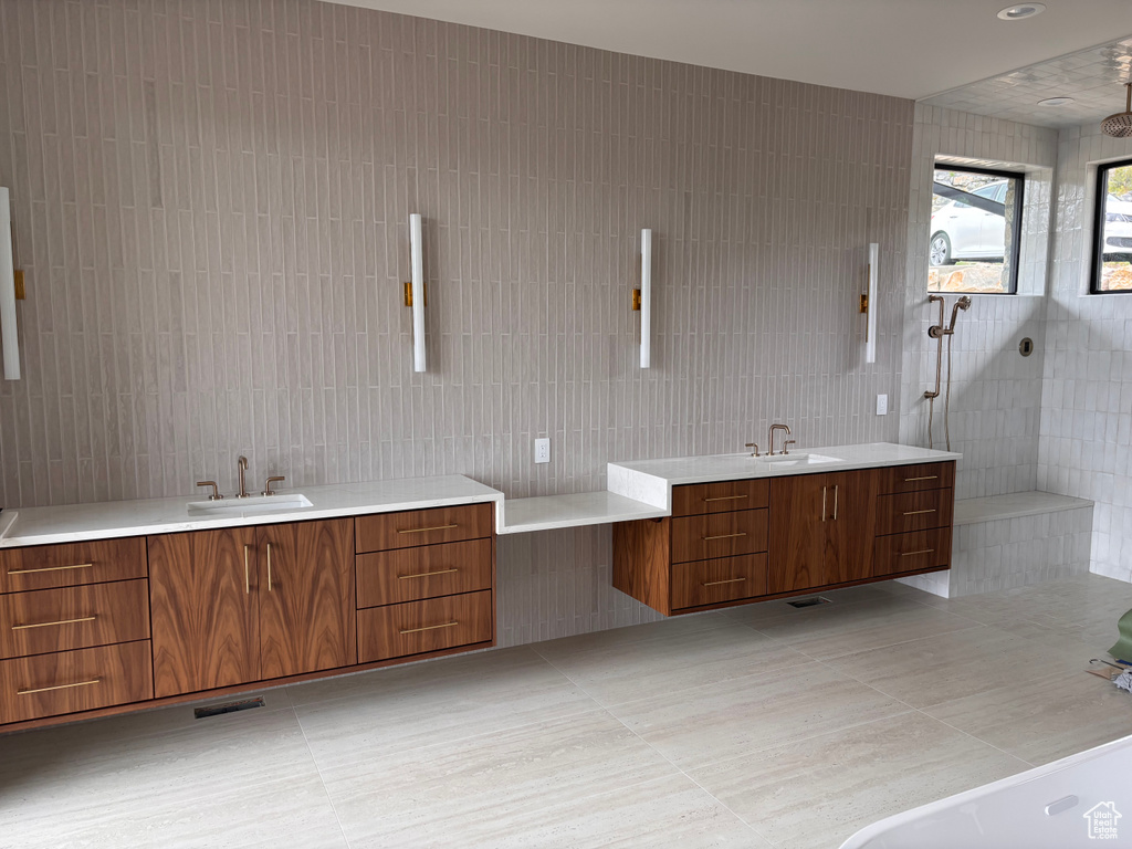 Bathroom featuring tile walls, vanity, tile patterned floors, and backsplash