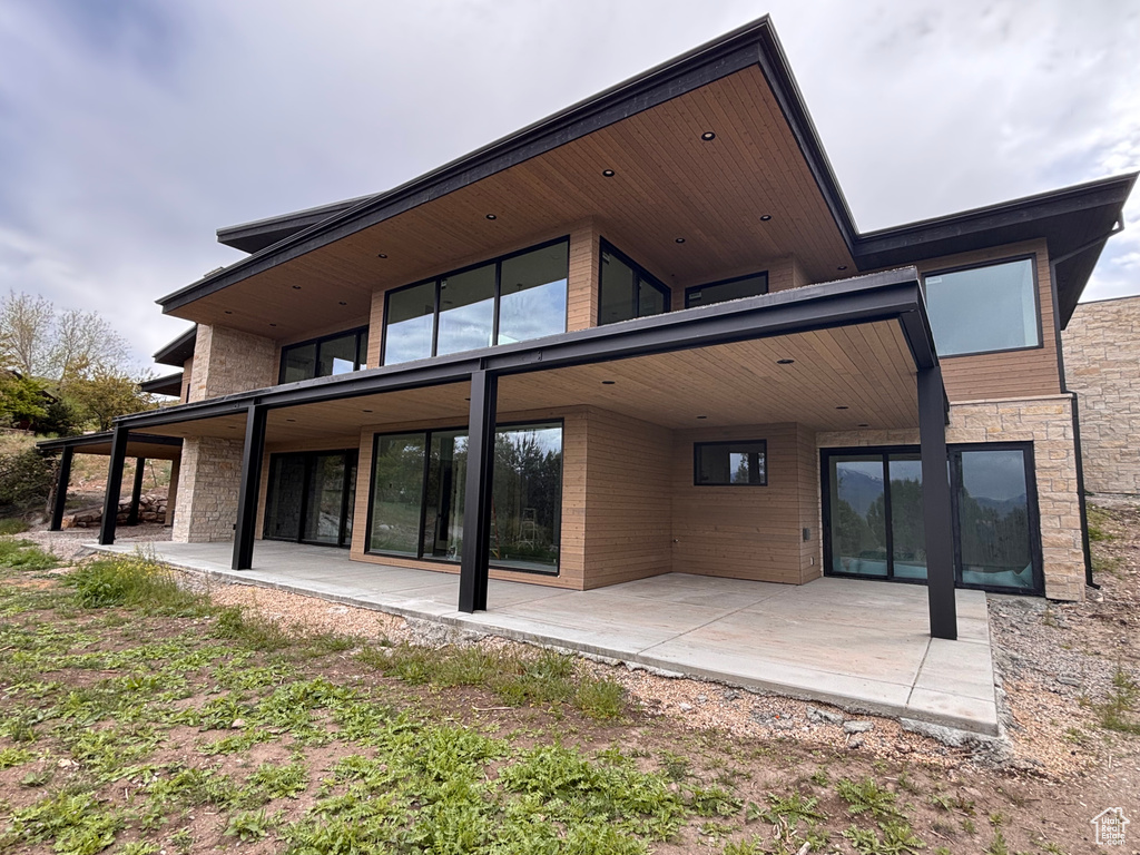 Rear view of property with a patio and stone siding