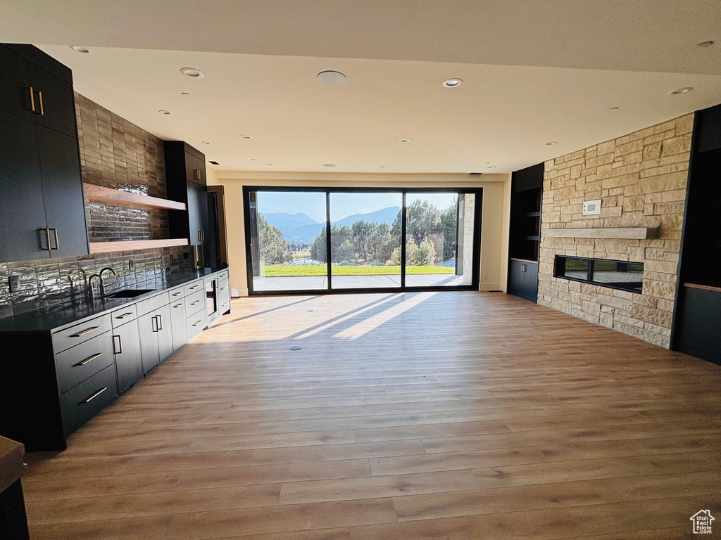 Unfurnished living room featuring light wood-style floors, a stone fireplace, recessed lighting, and a mountain view
