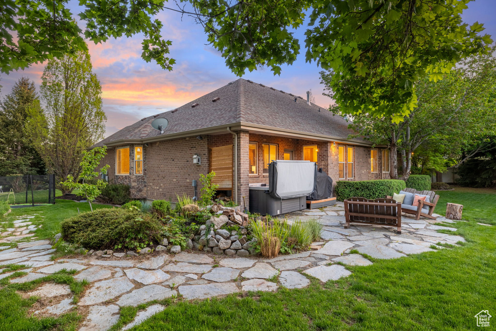 Rear view of house featuring an outdoor hangout area, a patio, brick siding, roof with shingles, and a hot tub