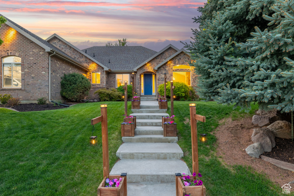 View of front of home with a front yard, brick siding, and a shingled roof