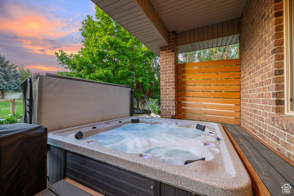 Patio terrace at dusk featuring a hot tub