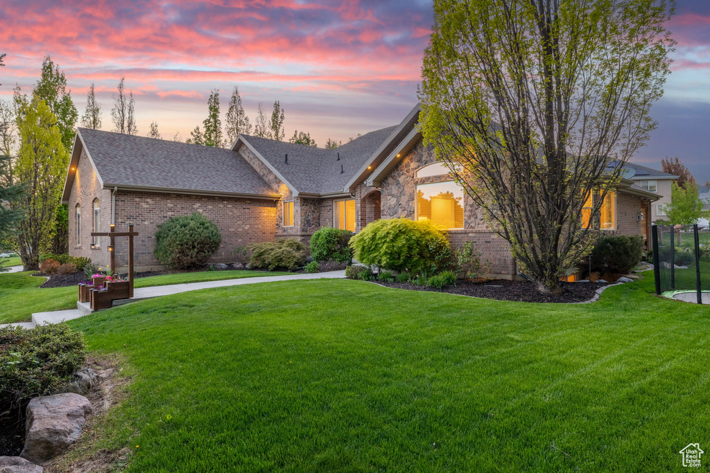 View of front of property featuring a lawn, brick siding, and roof with shingles