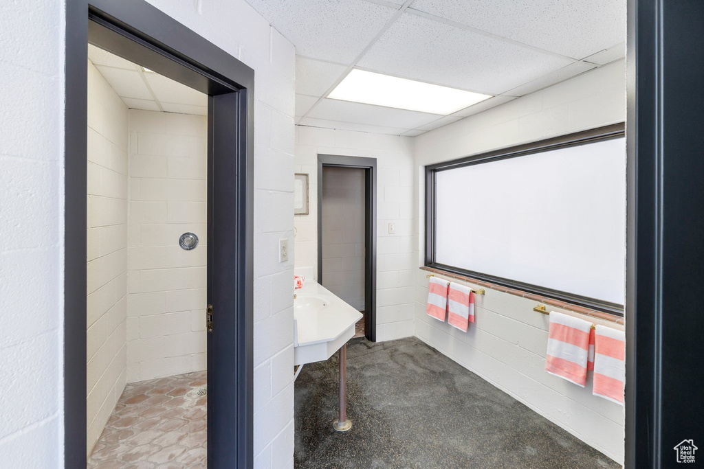 Bathroom featuring concrete block wall and a drop ceiling
