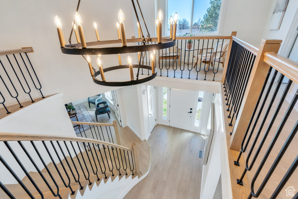 Foyer entrance with an inviting chandelier, stairs, and wood finished floors