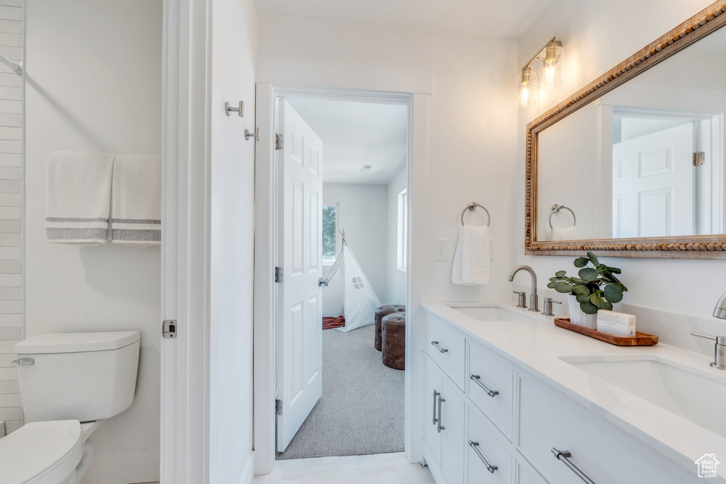 Full bath featuring double vanity, a sink, and toilet