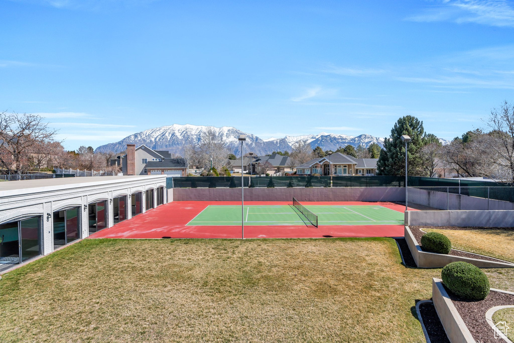 View of tennis court featuring a lawn, fence, and a mountain view