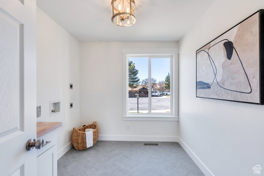 Interior space featuring washer hookup, hookup for an electric dryer, laundry area, baseboards, and an inviting chandelier