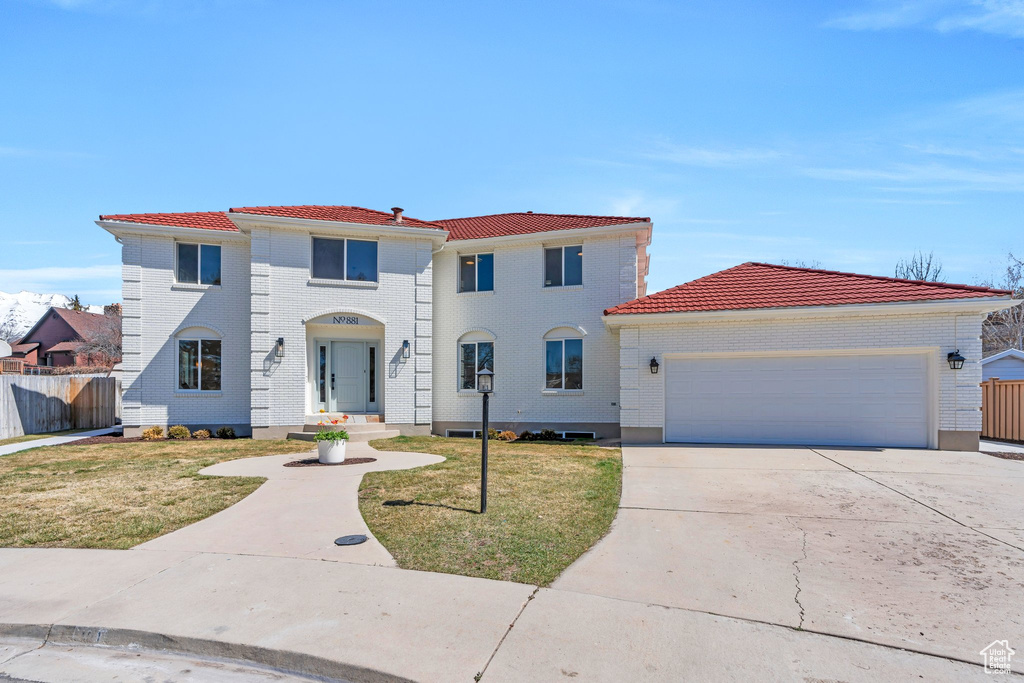 Mediterranean / spanish-style house with driveway, a front yard, a tile roof, fence, and a garage