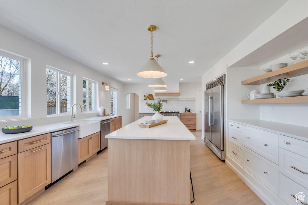 Kitchen featuring open shelves, light wood-style floors, a kitchen island, and appliances with stainless steel finishes