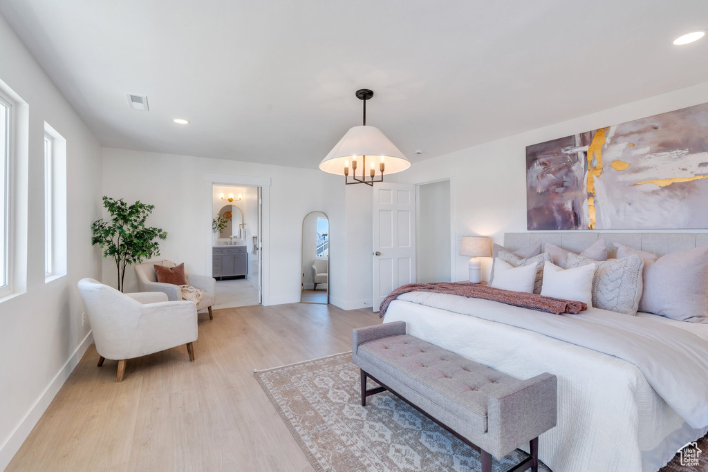 Bedroom featuring arched walkways, baseboards, visible vents, and light wood-style floors