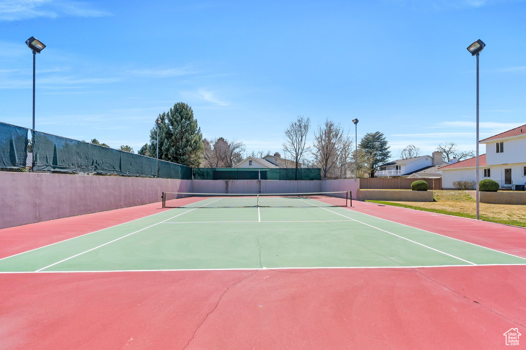 View of tennis court with community basketball court and fence