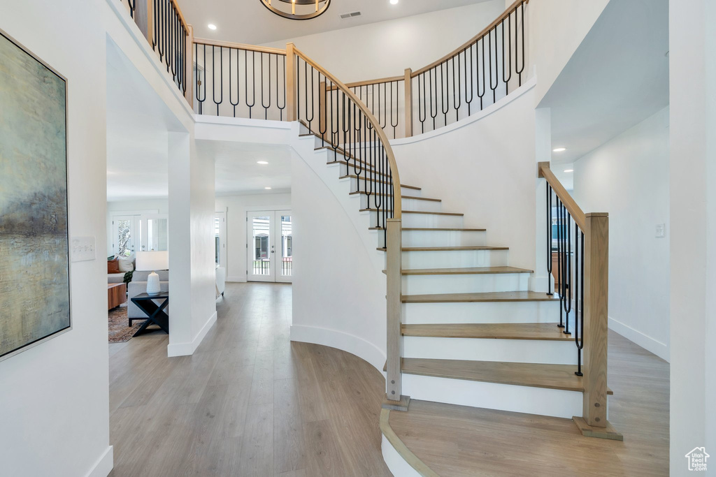 Stairway featuring a high ceiling, visible vents, baseboards, and wood finished floors