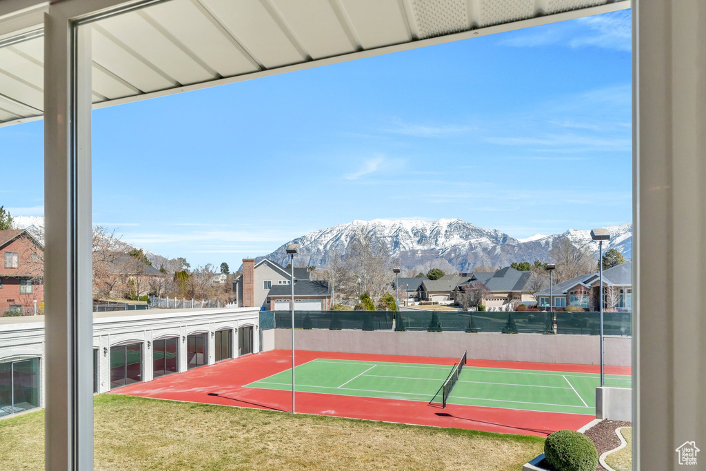 View of sport court featuring a yard, a mountain view, fence, and a residential view