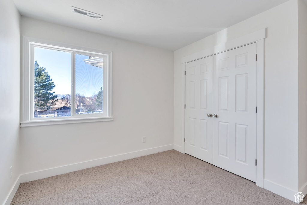 Unfurnished bedroom with carpet flooring, a closet, baseboards, and visible vents