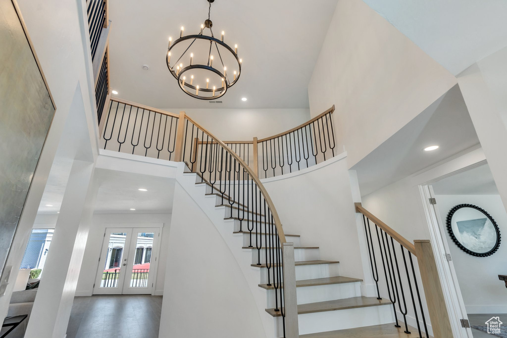 Stairway with an inviting chandelier, a towering ceiling, french doors, and recessed lighting