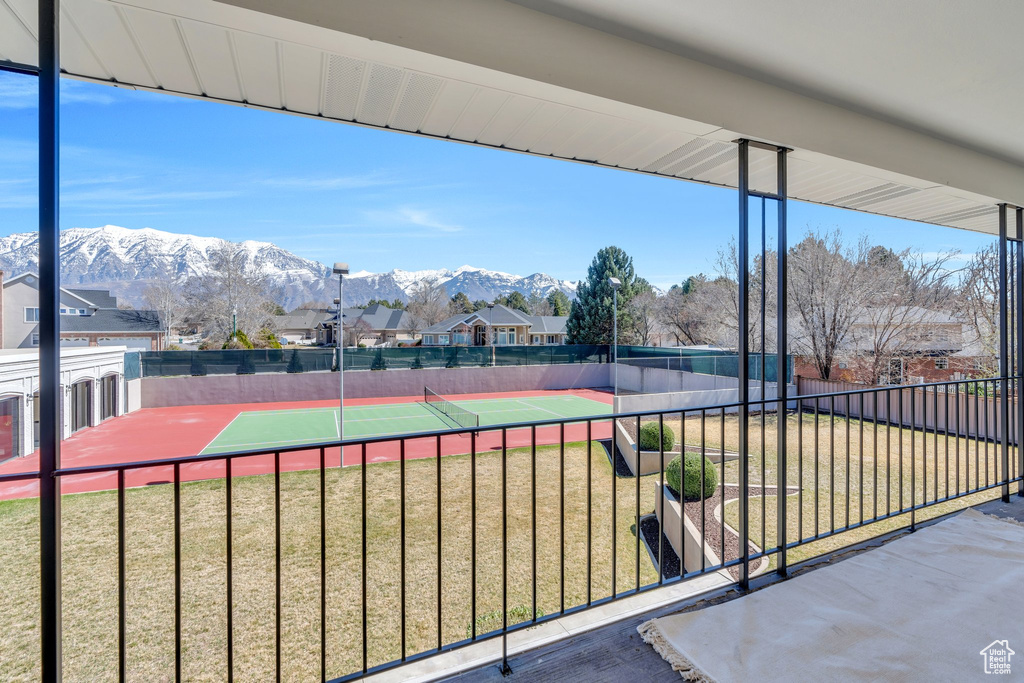 View of sport court with fence, a mountain view, and a yard