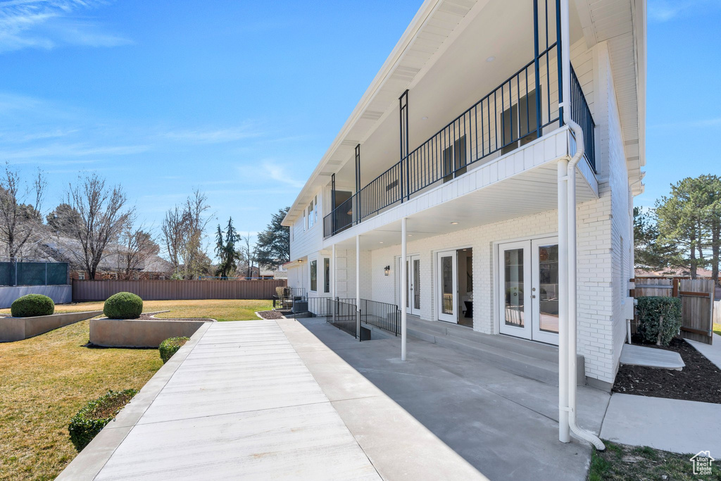 View of patio with a balcony, fence, and french doors