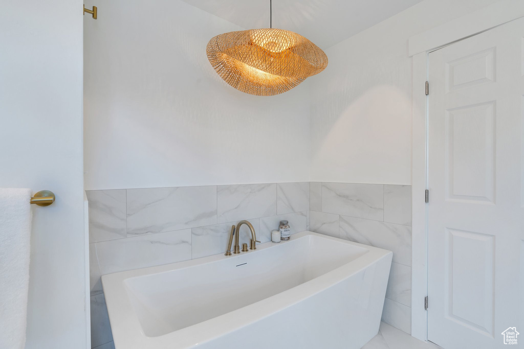 Full bath with a bathing tub and tile walls