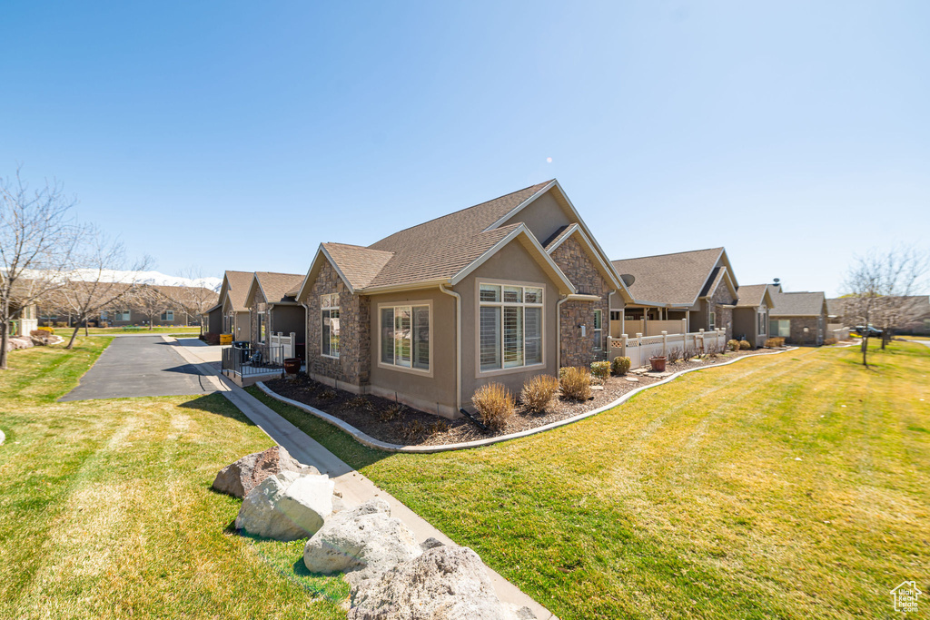 View of front of house with a front lawn, stucco siding, stone siding, and aphalt driveway