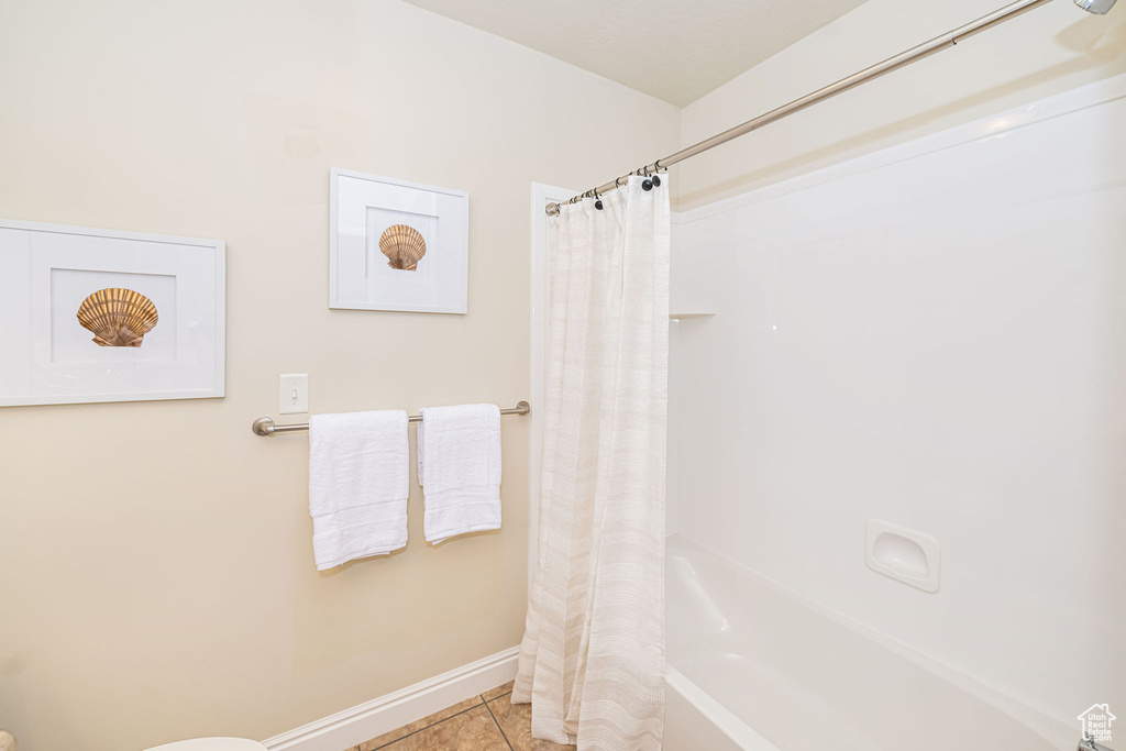 Full bathroom featuring baseboards, shower / tub combo with curtain, and tile patterned floors