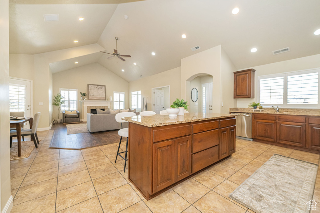 Kitchen featuring dishwasher, ceiling fan, a breakfast bar area, a center island, and light tile patterned floors