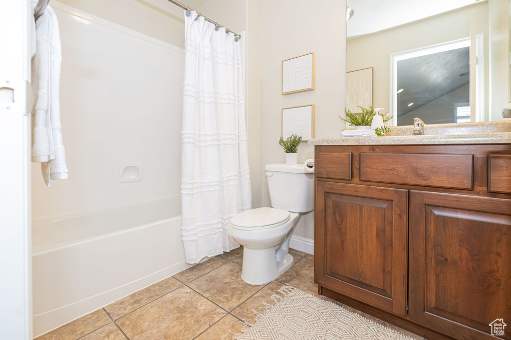 Full bath with shower / bath combo with shower curtain, toilet, vanity, and tile patterned flooring