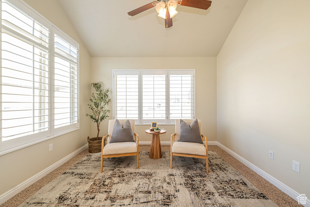 Sitting room featuring baseboards, vaulted ceiling, a ceiling fan, and a healthy amount of sunlight