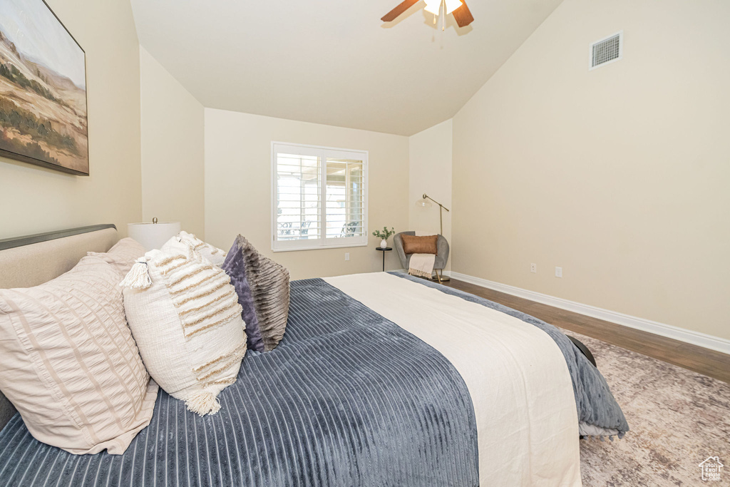 Bedroom featuring baseboards, visible vents, wood finished floors, and vaulted ceiling