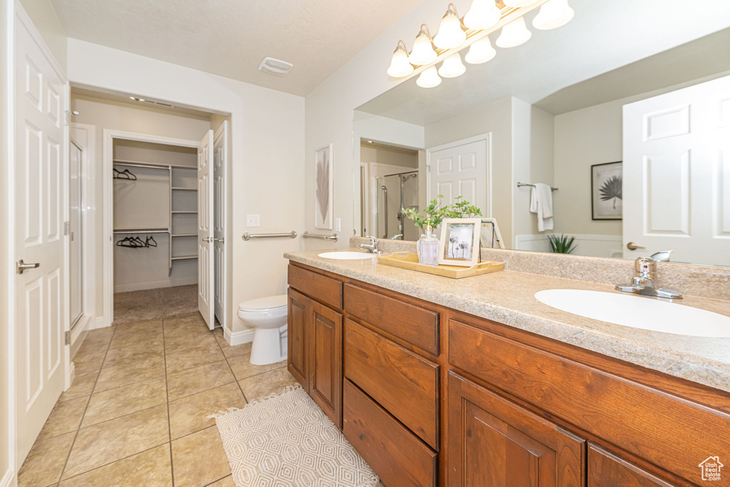 Bathroom featuring double vanity, a sink, toilet, and tile patterned flooring